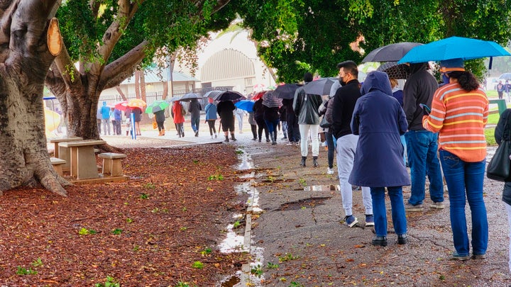 People stand in line under the rain for a free COVID-19 test outside the Lincoln Park Recreation Center in Los Angeles on Thursday.