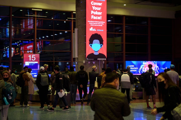 A sign reminds airline passengers to wear face masks as they wait to collect bags from a baggage carousel at the Harry Reid International Airport on January 2 in Las Vegas.