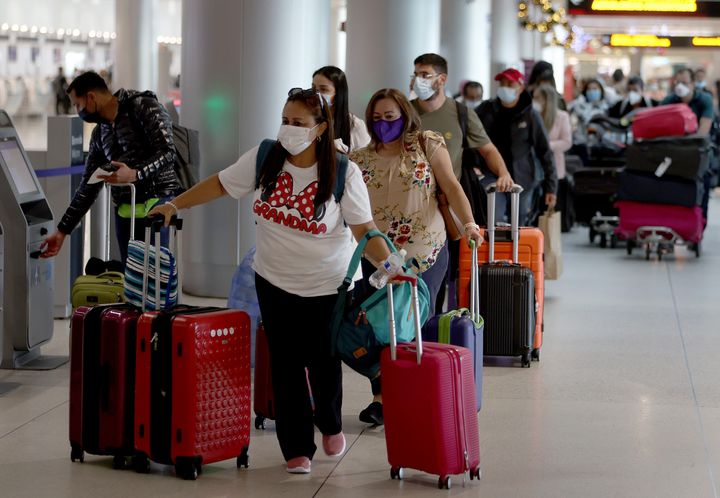 Masked travelers make their way through Miami International Airport on December 28 in Miami.