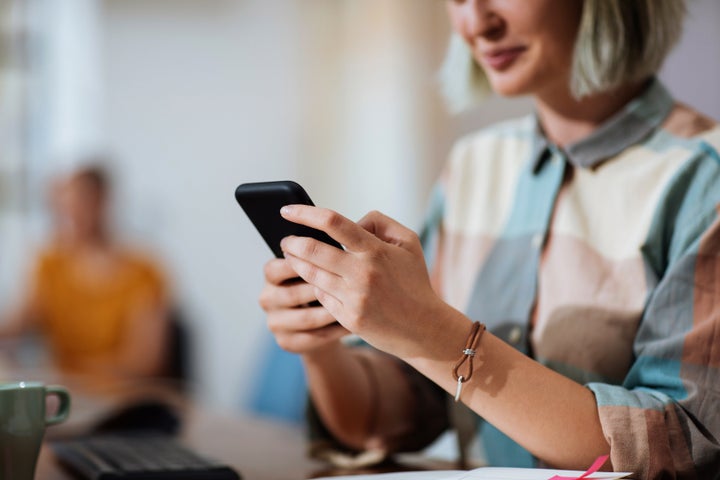 Unrecognisable woman using her phone while sitting in her office