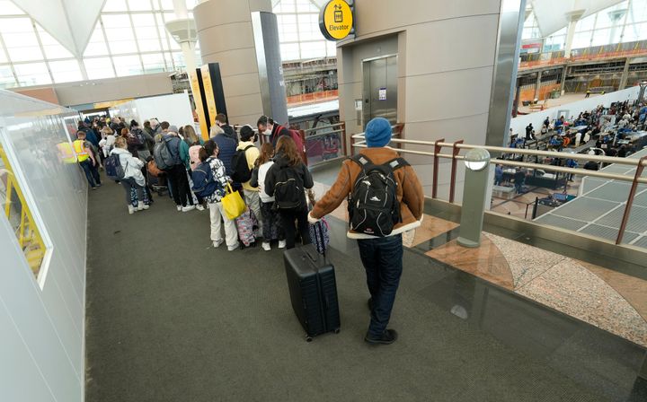 Passengers queue up to check in at the counter for American Airlines on Jan. 3, 2022, as the line snakes into the main terminal of Denver International Airport.