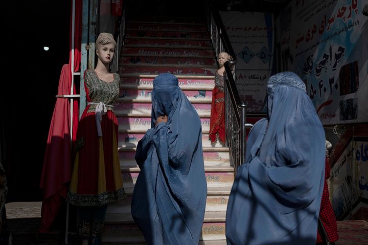 Αφγανές που φορούν μπούρκα περνούν μπροστά από ένα κατάστημα ρούχων, στο Χεράτ του Αφγανιστάν, Τρίτη, 23 Νοεμβρίου 2021. (AP Photo/Petros Giannakouris)