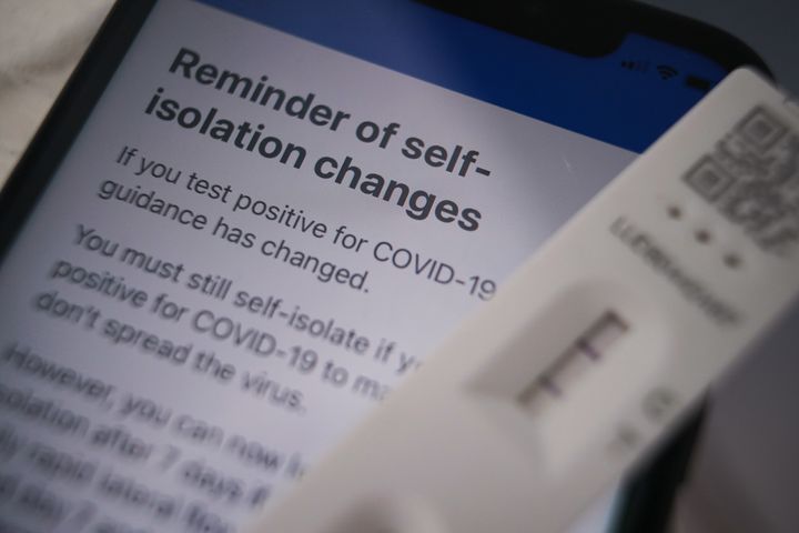 A positive lateral flow test cassette and advice from the NHS Covid app.