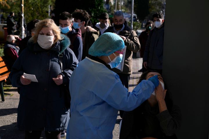 Υγειονομικό προσωπικό διενεργεί ράπιντ τεστ COVID-19 σε γυναίκα στην Αθήνα, ενώ άλλοι πολίτες στέκονται στην ουρά, τη Δευτέρα 3 Ιανουαρίου 2022. Η παραλλαγή Όμικρον είναι ήδη κυρίαρχη στα νέα κρούσματα που καταγράφονται στην Ελλάδα, ενώ καταγράφεται μεγάλη έξαρση. (AP Photo/Thanassis Stavrakis)