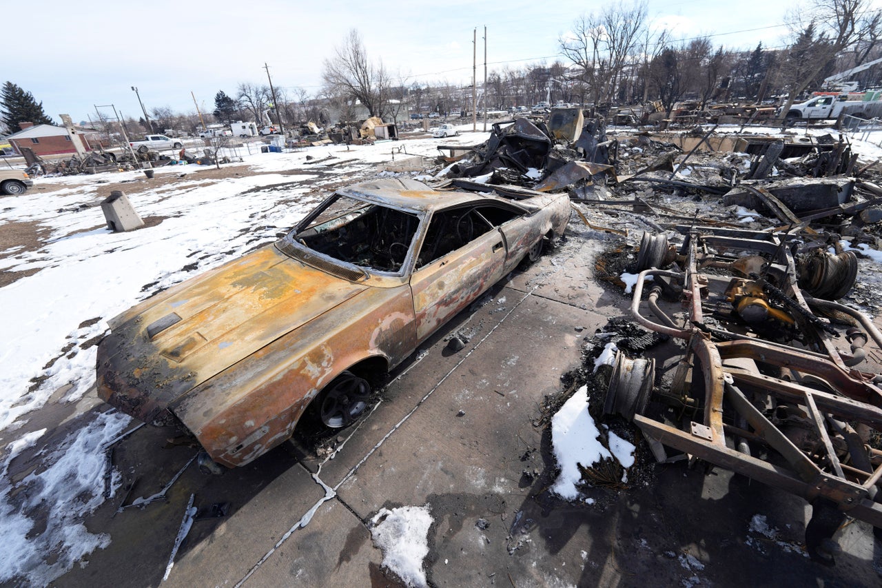 Charred vehicles sit amid the rubble of a home destroyed by wildfires Wednesday in Superior, Colorado.