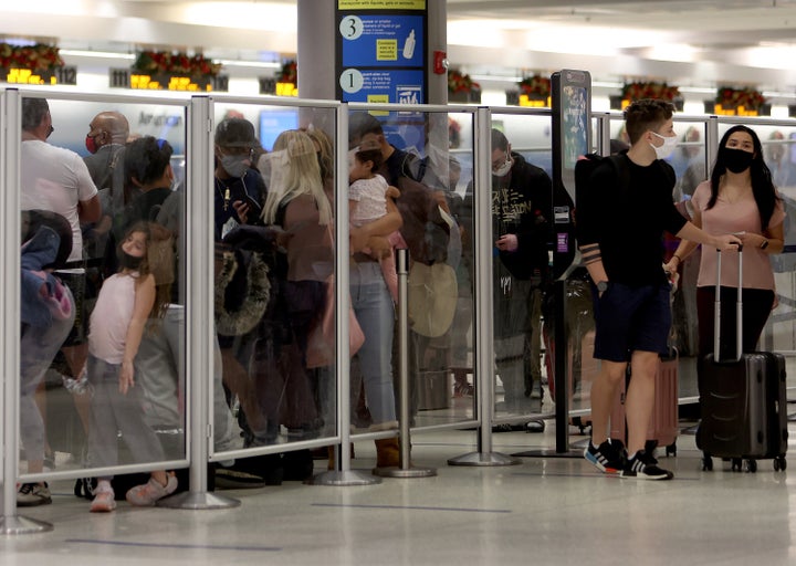 Travelers wait in a TSA security line as they make their way through Miami International Airport on Dec. 28. Over the Christmas holiday weekend, more than 2,000 flights were canceled as airlines dealt with a surge in COVID-19.
