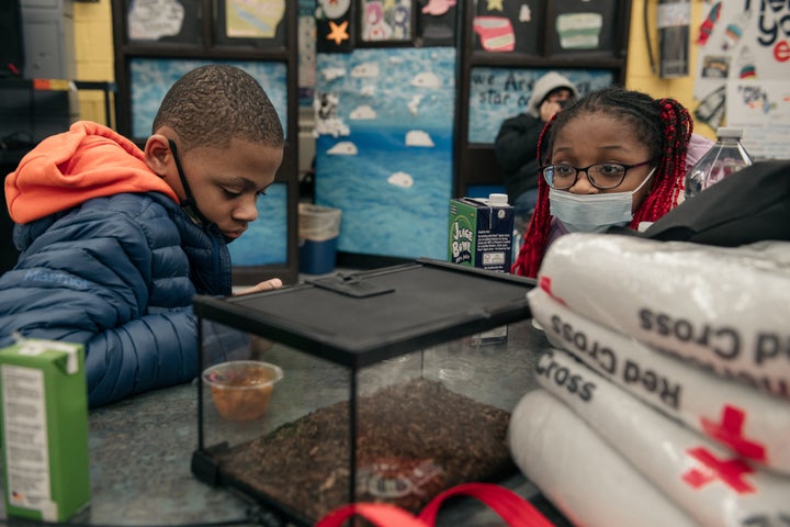 Jordan Mance (left) and his sister Jayden Mance take refuge with their pet gecko at a school cafeteria after a fire at their apartment building erupted.