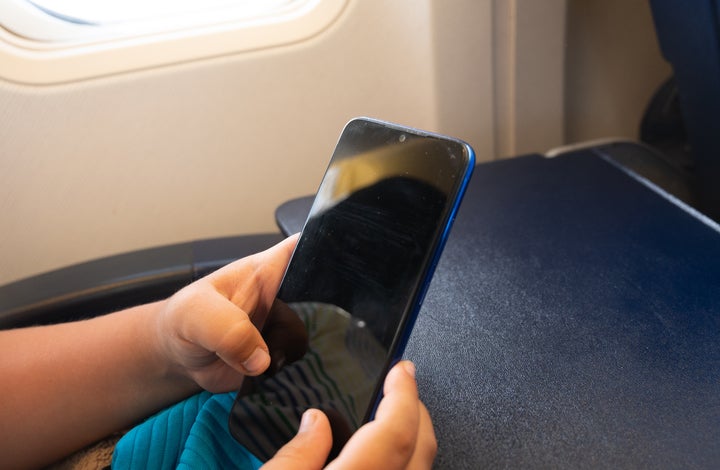 Una persona envía un mensaje con el móvil desde un avión.