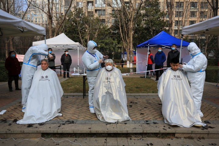 Hairdressers wearing protective suits cut residents' hair at a residential block which has become under lockdown in Xi'an in northwest China's Shaanxi province on Jan. 9, 2022.