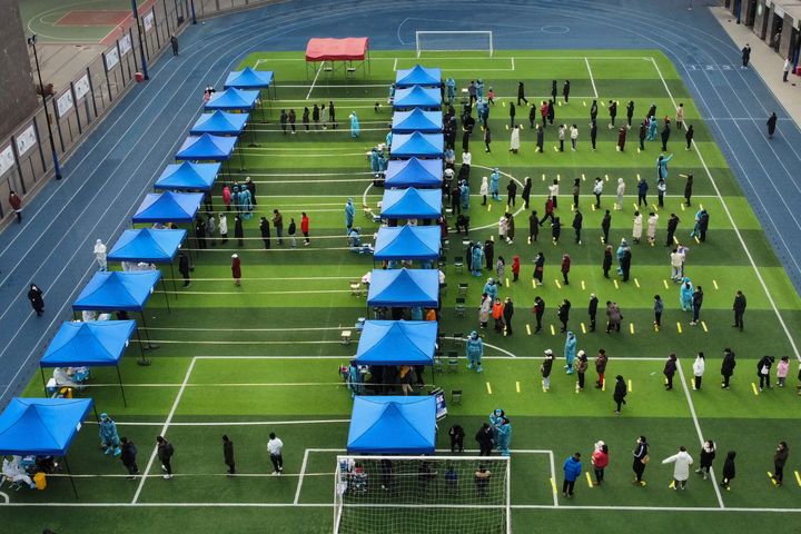 In this photo released by Xinhua News Agency, residents line up on a football field for the coronavirus test during a mass testing in north China's Tianjin municipality, on Jan. 9, 2022. 