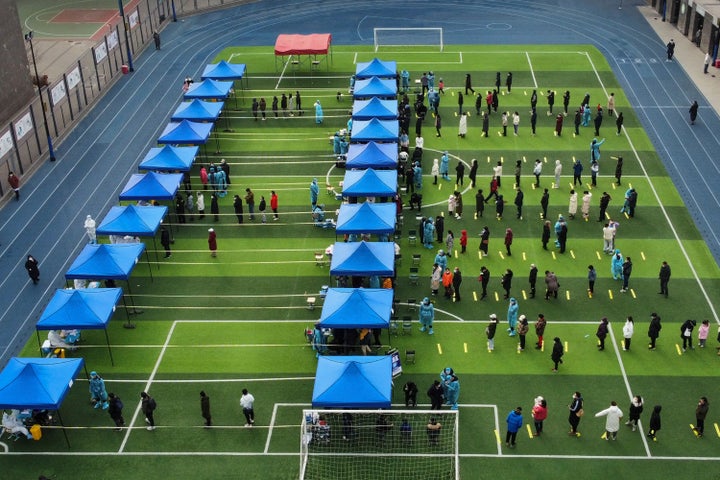 In this photo released by Xinhua News Agency, residents line up on a football field for the coronavirus test during a mass testing in north China's Tianjin municipality, on Jan. 9, 2022.
