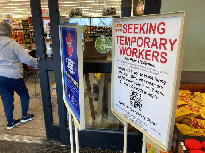 A sign advertising the need for temporary workers stands next to the entrance of a King Soopers grocery store on Jan. 6, 2022, in southeast Denver. The advertised $18 per hour for temporary workers is $2 higher than the pay floor being offered in contract negotiations.