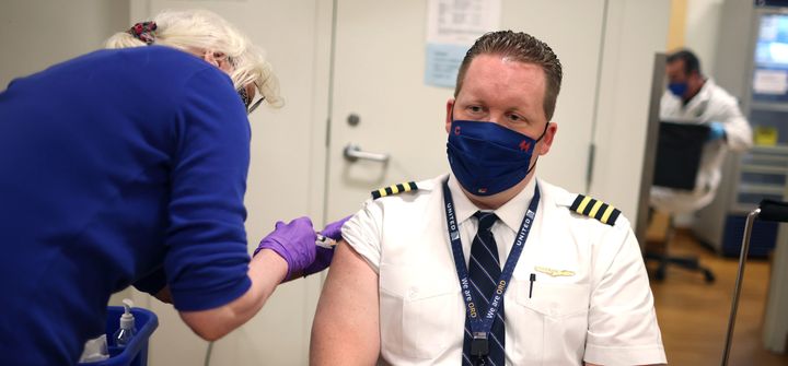 United Airlines pilot Steve Lindland receives a COVID-19 vaccine from RN Sandra Manella at United's onsite clinic at O'Hare International Airport on March 9, 2021. in Chicago, Illinois.