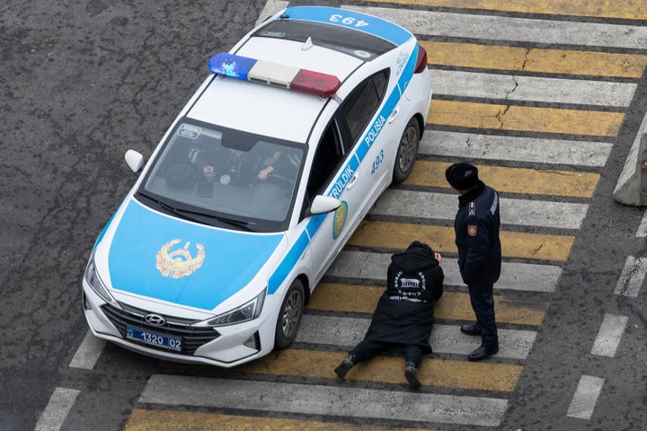 A police officer watches over a man as his papers are checked by colleagues at a crossing, on a street in Almaty, Kazakhstan, on Jan. 10, 2022.