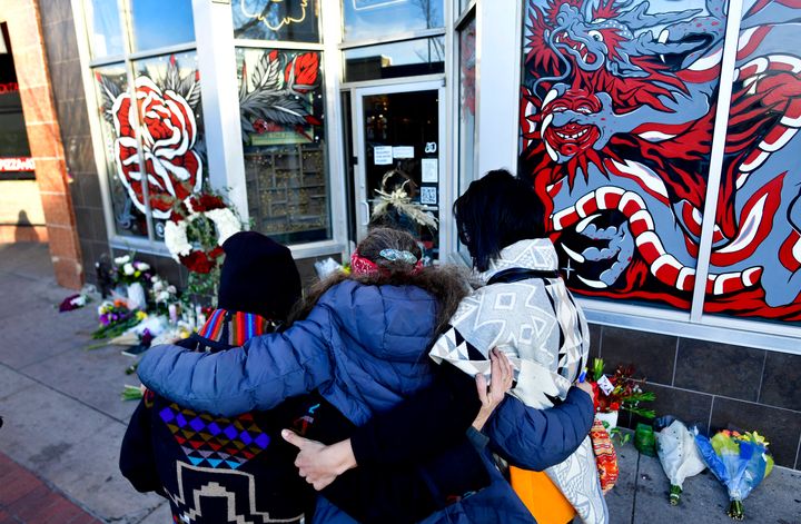 Jeanette Vizguerra, Elena Klaver and Miranda Encina hug one another in front of a makeshift memorial outside Sol Tribe Custom Tattoo and Body Piercing shop in Denver on Dec. 28, 2021.