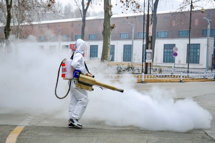 A volunteer wearing personal protective equipment sprays disinfectant at a park on Jan. 11 in Zhengzhou, China.