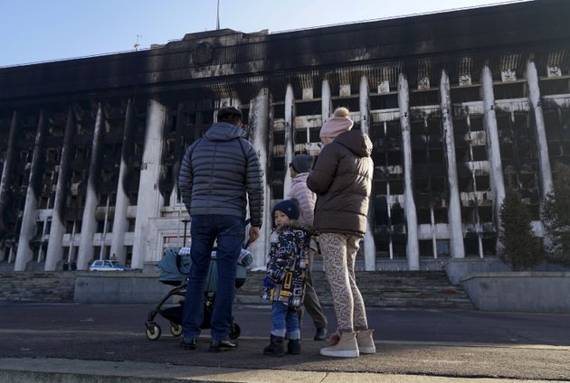 Una familia pasea ante un edificio quemado en las protestas, en la antigua capital,