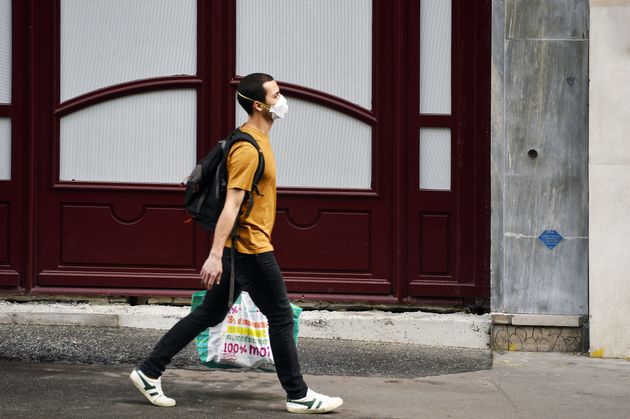 Homme avec un masque portant un sac de courses dans la rue le 18 avril 2020, Paris, France. (Photo by...