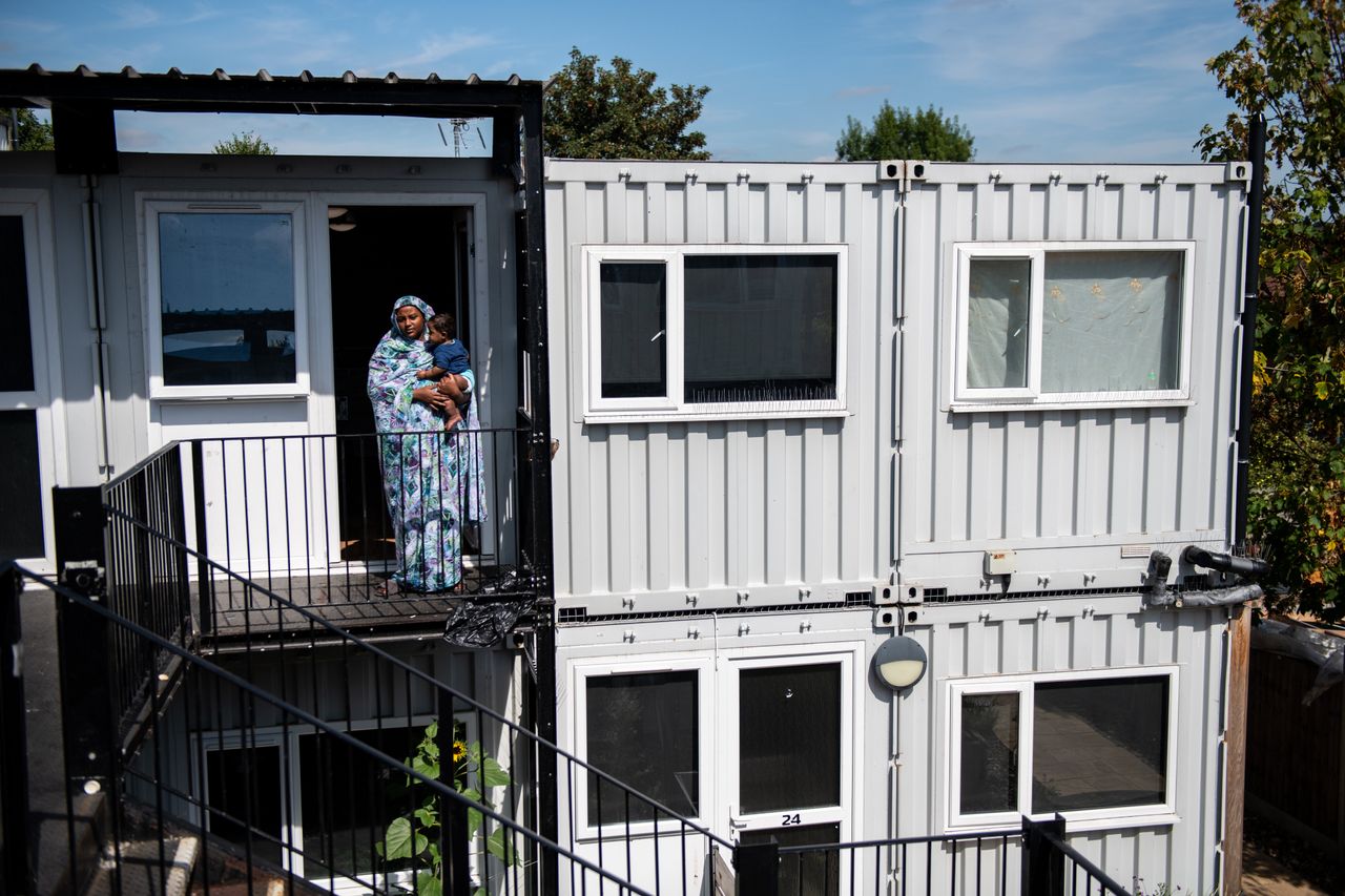 A mother poses for a photograph with her seven-month-old son outside a development of converted shipping containers in 2019 in Hanwell.