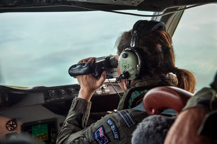 A crew member from an Orion aircraft looks out the window as it flies over Tonga after the volcanic eruption.