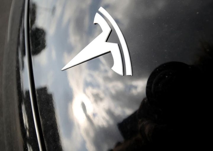 In this July 8, 2018, file photo, clouds are reflected above the company logo on the hood of a Tesla vehicle outside a showroom in Littleton, Colo. 