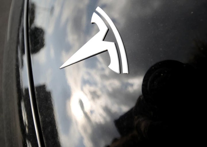 In this July 8, 2018, file photo, clouds are reflected above the company logo on the hood of a Tesla vehicle outside a showroom in Littleton, Colo.