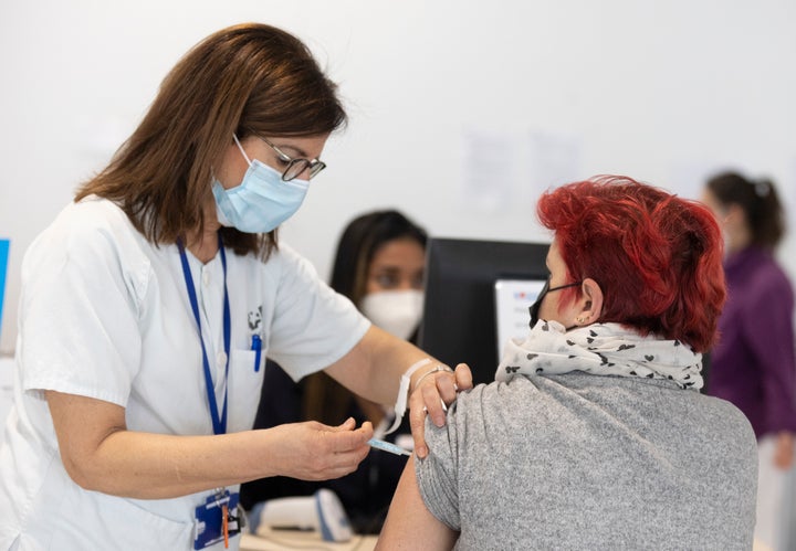 Una sanitaria inyecta el antiviral a un mujer adulta