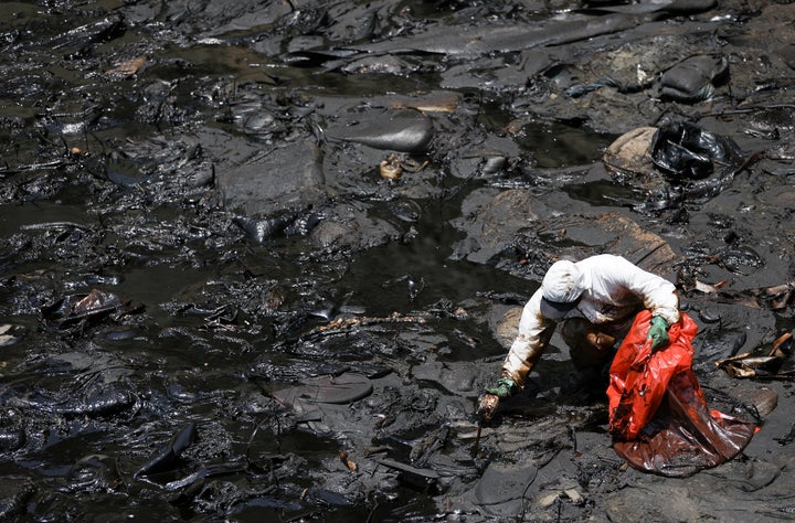 A worker cleans up an oil spill on the Peruvian beach in Ventanilla that was caused by abnormal waves, triggered by a massive underwater volcanic eruption half a world away in Tonga.