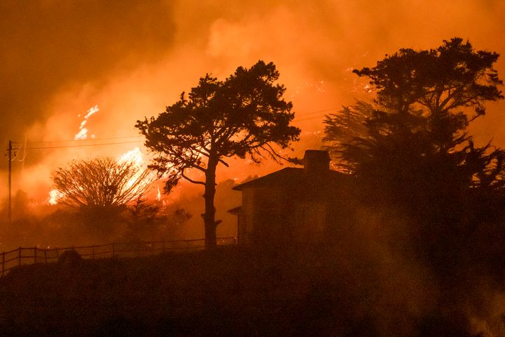 The Colorado Fire burns behind a house off Highway 1 near Big Sur, Calif., Saturday, Jan. 22, 2022.