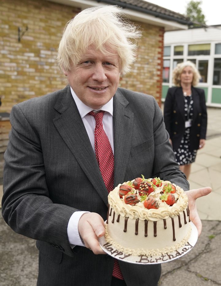 Boris Johnson holds up a birthday cake - baked for him by school staff - during a visit to Bovingdon Primary Academy. The Prime Minister is facing fresh allegations of breaking coronavirus rules after it emerged that a gathering to wish him a happy birthday was held inside No 10 during the first lockdown.