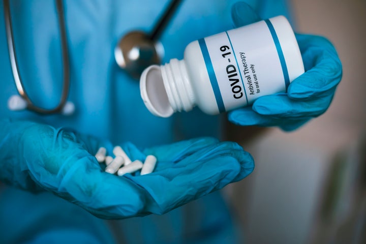 Médico con un bote de pastillas contra la covid-19.