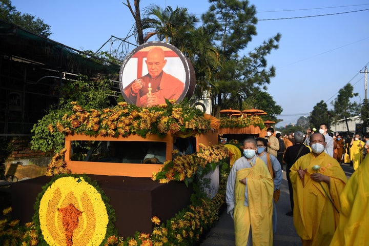 Buddhist followers walk by the convoy carrying the coffin of Vietnamese monk Thich Nhat Hanh,one of the world's most influential and prominent religious leaders, to a cremation site in Hue province on January 29, 2022.