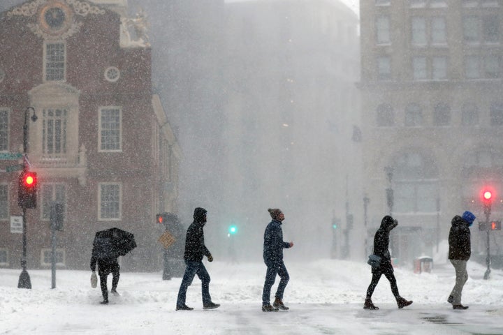 People cross Congress Street, Saturday, Jan. 29, 2022, in Boston. (AP Photo/Michael Dwyer)