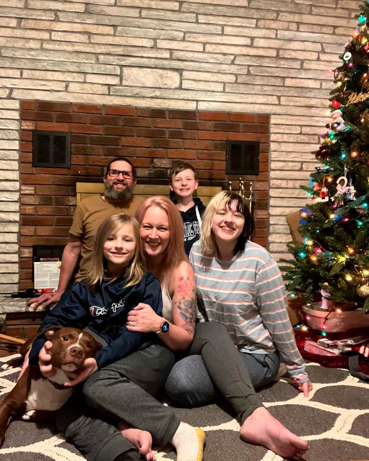 Rebekah Hogan, center, shows her with her family next to their Christmas tree at their home in Latham, N.Y. More than a year after a bout with COVID-19, Hogan still suffers from severe brain fog, pain and fatigue that leave her unable to do her nursing job or handle household activities.