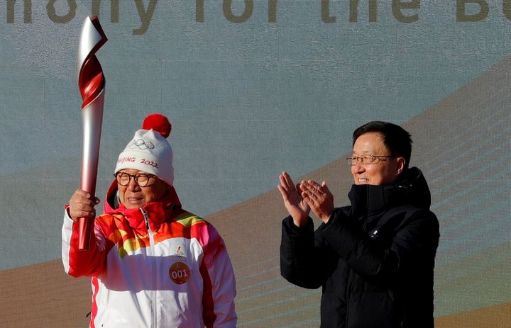 Πεκίνο, Κίνα - 2 Φεβρουαρίου 2022. Ο Αντιπρόεδρος της Κυβέρνησης Χαν Ζενγκ χειροκροτεί αφού παρέδωσε την Ολυμπιακή δάδα στον λαμπαδηδρόμο Λούο Ζιχουάν κατά την τελετή έναρξης στο Ολυμπιακό Δασικό Πάρκο. 