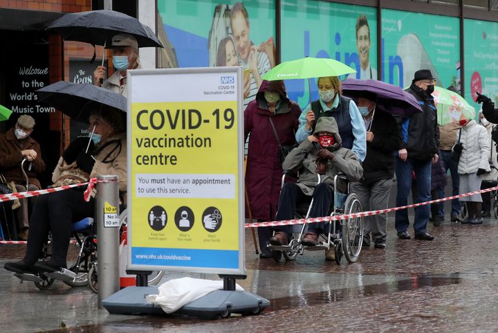 People queuing in bad weather to enter a Covid-19 vaccination centre in Folkestone, Kent.