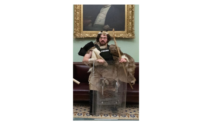 Aaron Mostofsky is seen inside the U.S. Capitol dressed in furs and carrying a walking stick while he loosely wears a bulletproof vest taken from an officer and holds a police riot shield on Jan. 6, 2021.