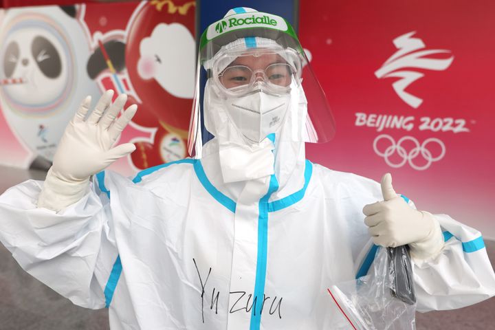 「Yuzuru」と書かれた防護服を着て、空港に到着した報道陣を迎える大会関係者＝30日、中国・北京