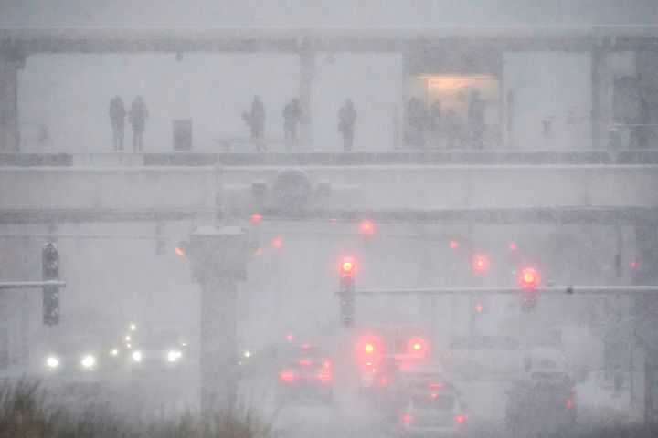 Motorists navigate Roosevelt Road in Chicago as rail commuters wait for a train at the elevated station during a winter storm on Feb. 2, 2022. 