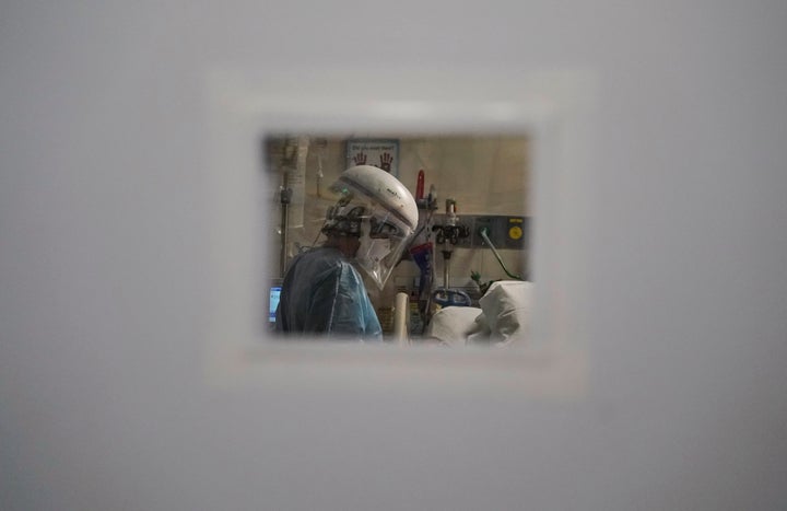 A nurse tending to a COVID-19 patient is seen through a small window in an intensive care unit at Mission Hospital in Mission Viejo, California.