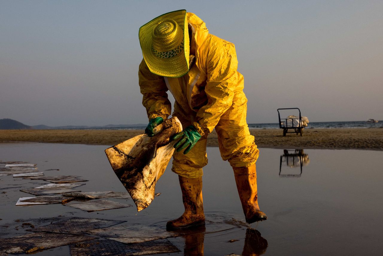 A worker cleans up crude oil Saturday on Mae Ram Phueng Beach in Thailand following a spill caused by a leak in an undersea pipeline owned by Star Petroleum Refining Public Co. in Rayong.