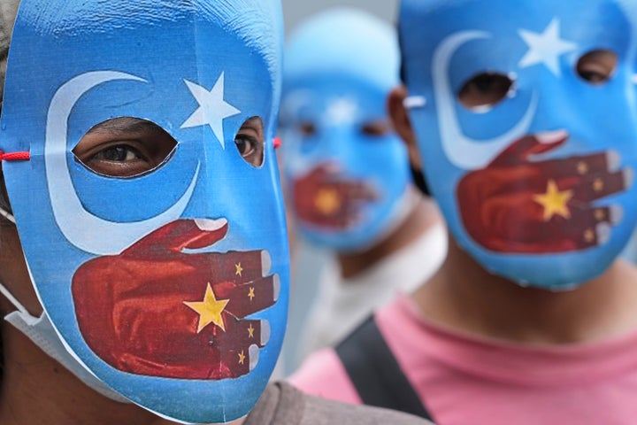 Student activists wear masks with the colors of the pro-independence East Turkistan flag during a rally to protest the Beijing 2022 Winter Olympic Games, outside the Chinese Embassy in Jakarta, Indonesia, Friday, Jan. 14, 2022. Dozens of students staged the rally demanding the cancellation of the Beijing Olympics over alleged human rights violations against Muslim Uyghur ethnic minority in China's region of Xinjiang.