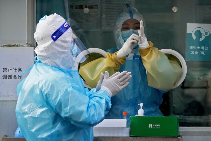 Medical workers wearing protective gear prepare swabs for people at a mobile coronavirus testing facility near a commercial office buildings in Beijing on Monday.