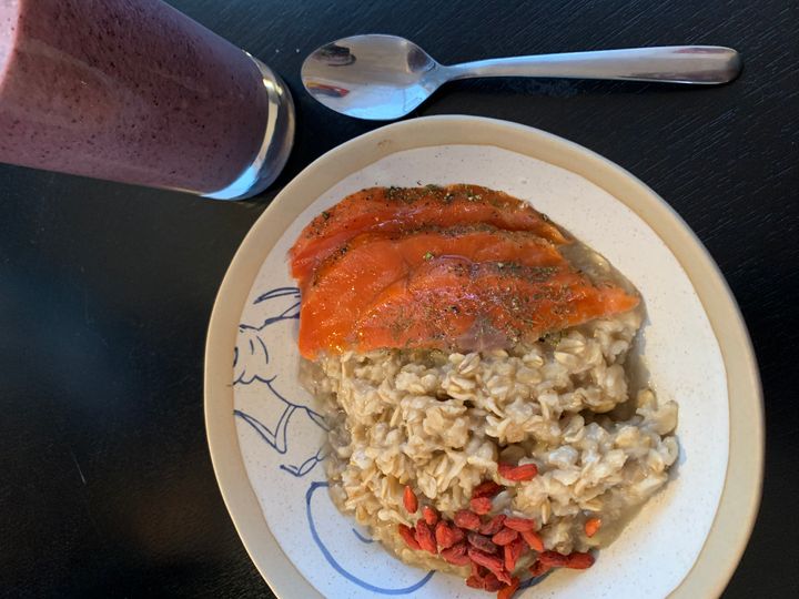 Brown sugar oatmeal topped with salmon gravlax and goji berries, and a blueberry smoothie.