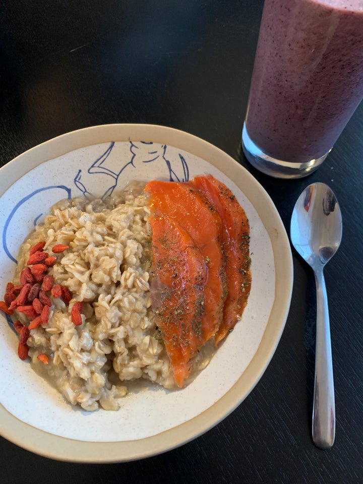 Brown sugar oatmeal topped with salmon gravlax and goji berries, and a blueberry smoothie.