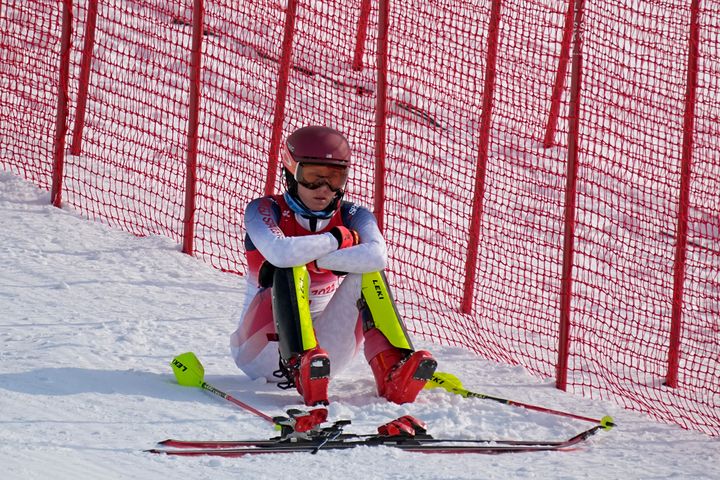 Mikaela Shiffrin sits on the side of the course after skiing out in the first run of the women's slalom in Beijing.