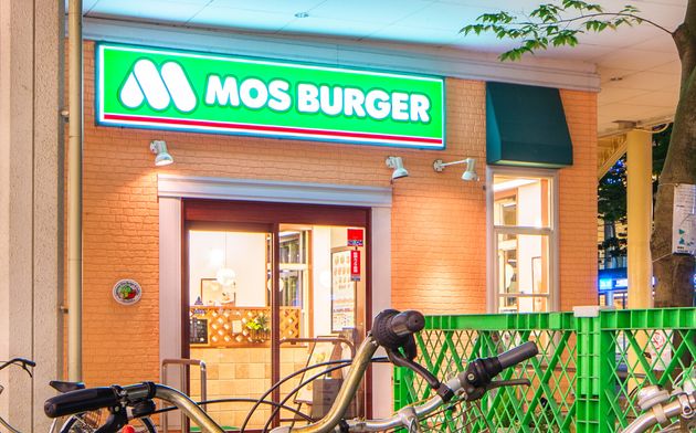 Mos Burger outlet at night in Niigata Japan with parked bicycles in the foreground.