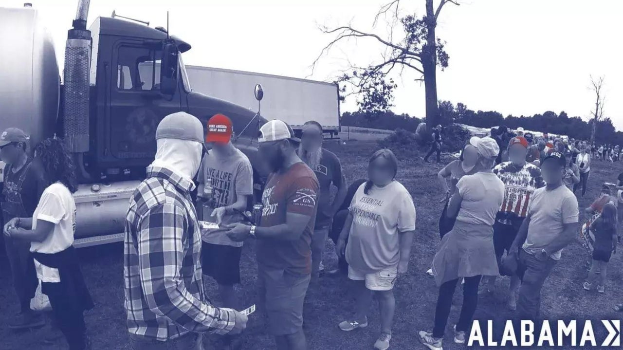 A masked Patriot Front member passes out the white supremacist group's propaganda at an August 2021 rally for former President Donald Trump rally in Cullman, Alabama.