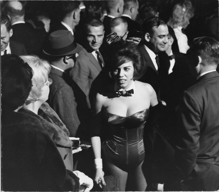 A woman working as a Playboy bunny walks through a crowd of men at the Playboy Club, Chicago, in the1960s.