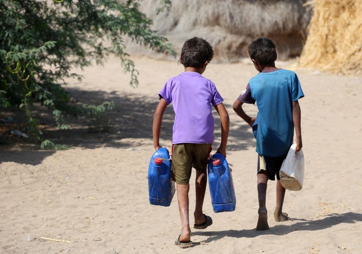 Yemeni children carry jerrycans at a makeshift camp for people who fled fighting between Houthi rebels and the Saudi-backed government forces, in the village of Hays near the conflict zone in Yemen's western province of Hodeida, on Jan. 28.